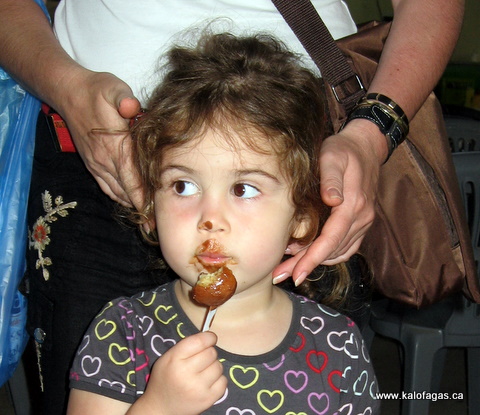 Cute Greek girl caught eating chocolatecovered Loukoumades at the Festival 